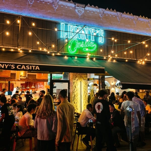 Lenny's Casita restaurant at night, with a neon sign, string lights, and patrons dining outside.