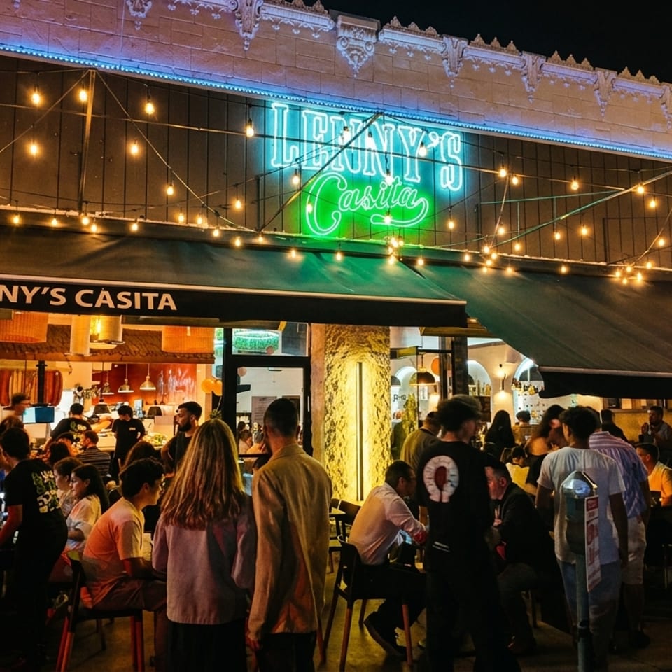 Lenny's Casita restaurant at night, with a neon sign, string lights, and patrons dining outside.