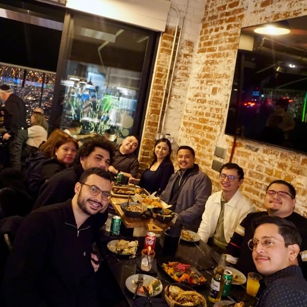 A group of friends enjoying dinner and drinks at a restaurant with a city view.