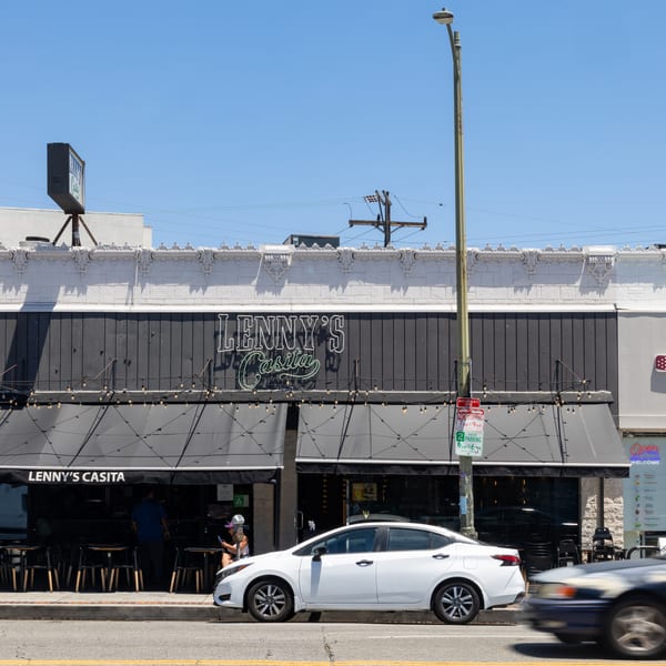 Lenny's Casita restaurant exterior with outdoor seating, black awnings, and a neon sign on a sunny day.