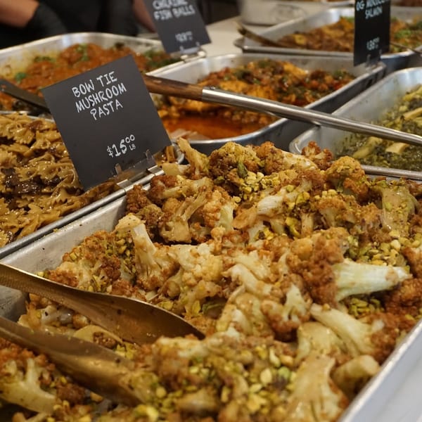 A buffet line with trays of Bow Tie Mushroom Pasta, roasted cauliflower, and other dishes.